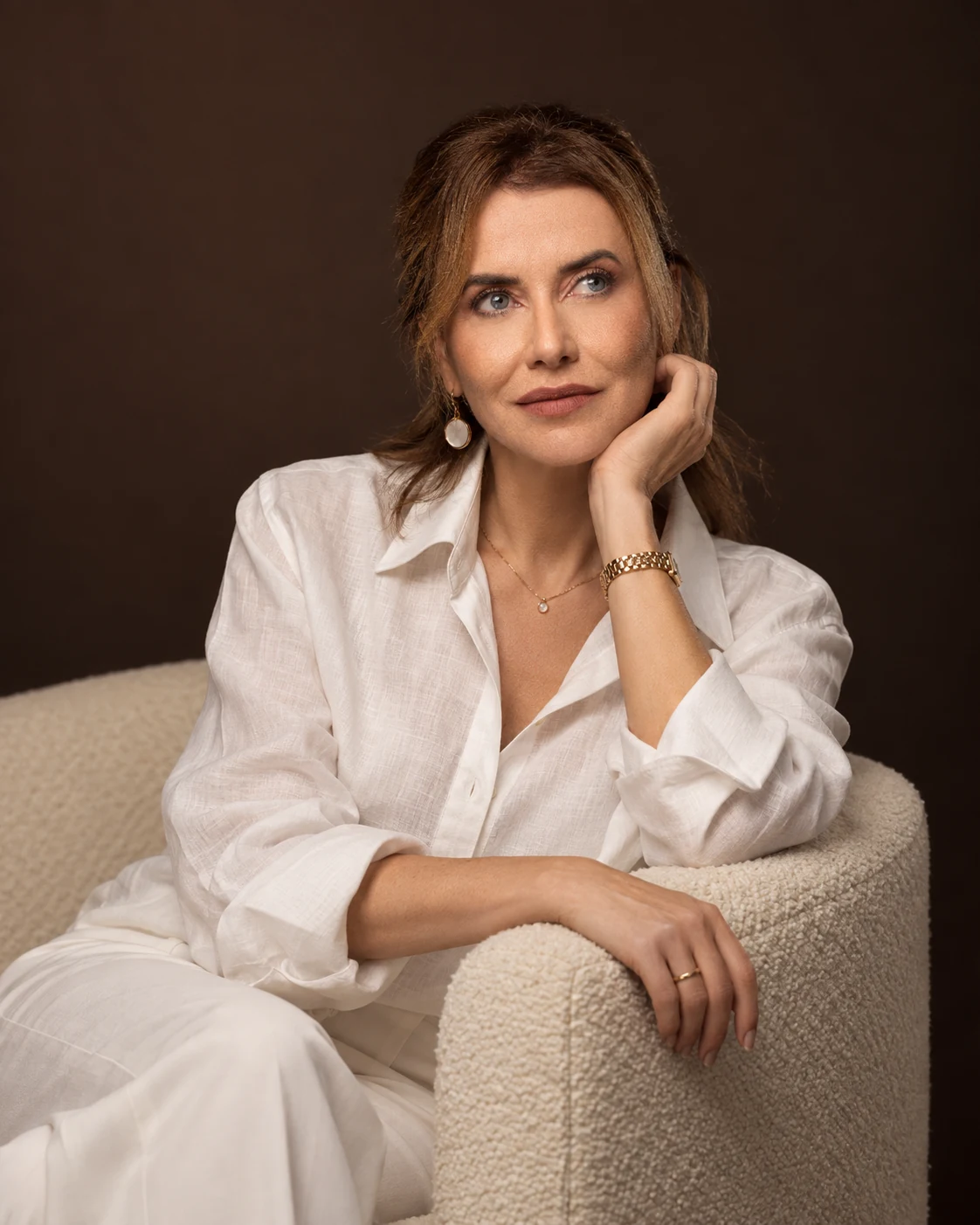 Retrato da Dra. Patrícia Pires, sentada em uma poltrona, com camisa branca